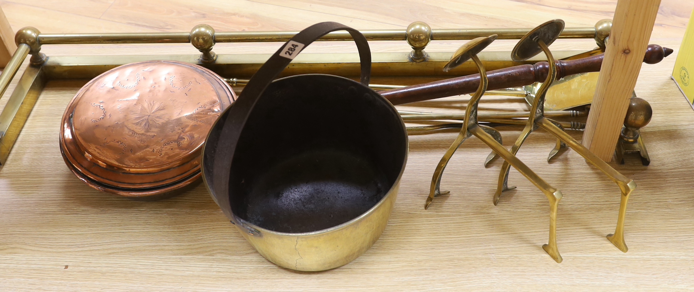 Brassware including fire kerb, fire tools, arts and crafts fire dogs and a copper warming pan, the largest 116cm wide